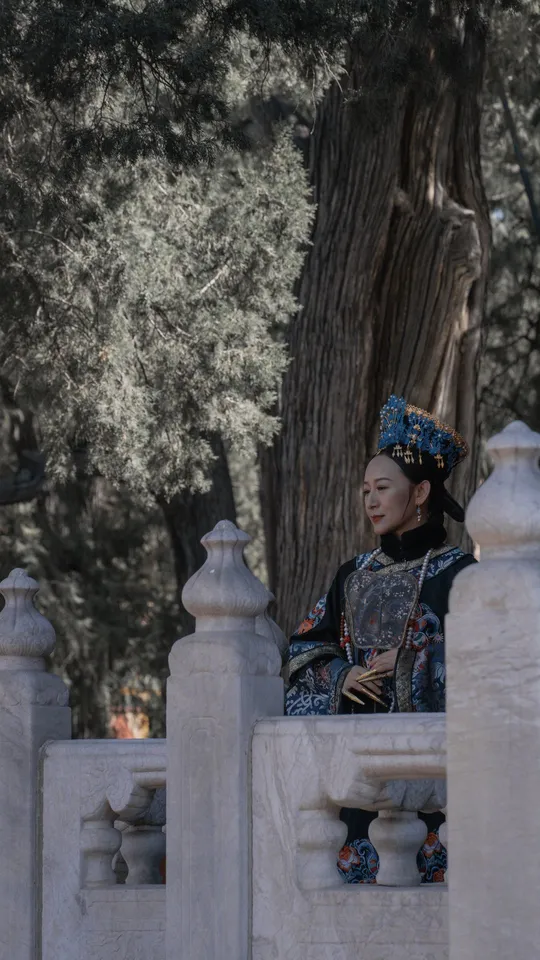 一位穿着传统服装的年轻女子坐在白色围墙上