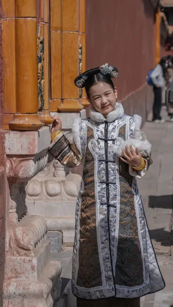 一位穿着传统服装的年轻女子站在街角一栋建筑前。