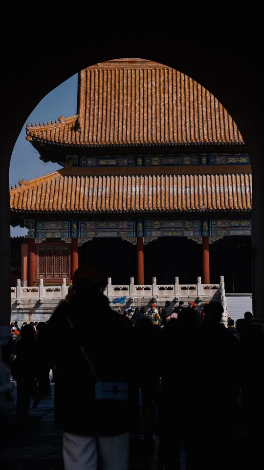 游客穿过紫禁城入口处的大型建筑的拱门。