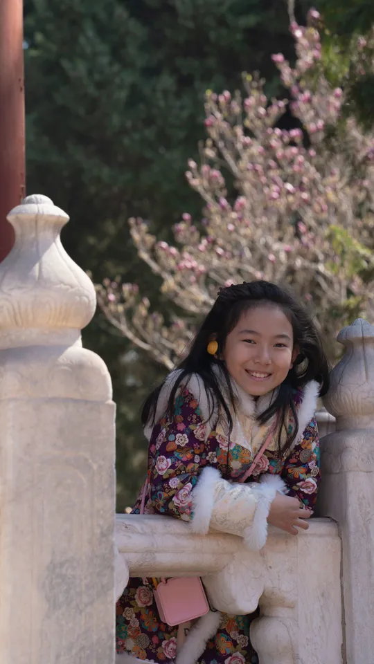 一个小女孩穿着传统的和服微笑着 靠在寺庙的围墙上