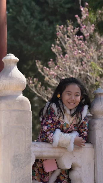 一个小女孩穿着传统的和服微笑着 靠在寺庙的围墙上