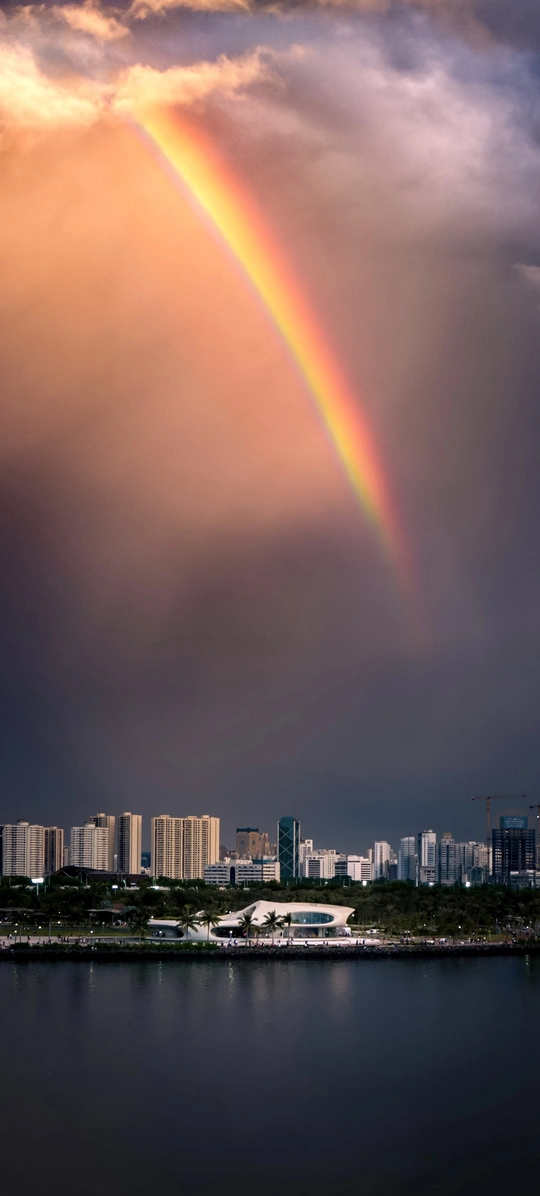 雨云中出现双彩虹 城市和水面之上。