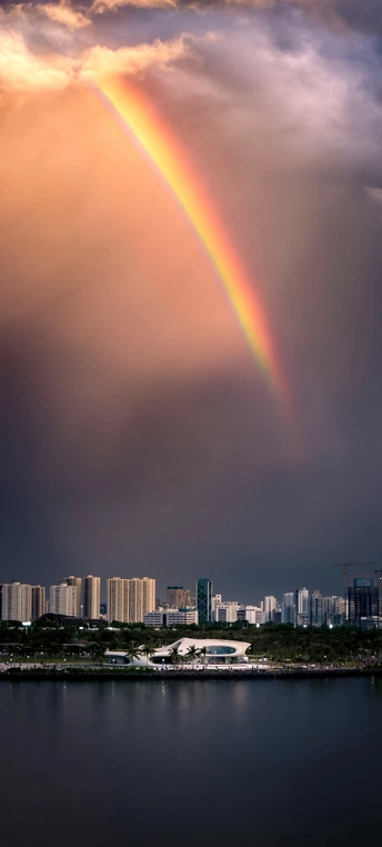 雨云中出现双彩虹 城市和水面之上。