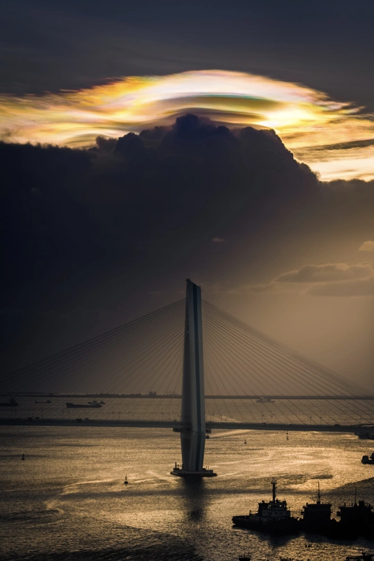 夕阳下跨过一片广阔的水域 天空中云朵飘荡。
