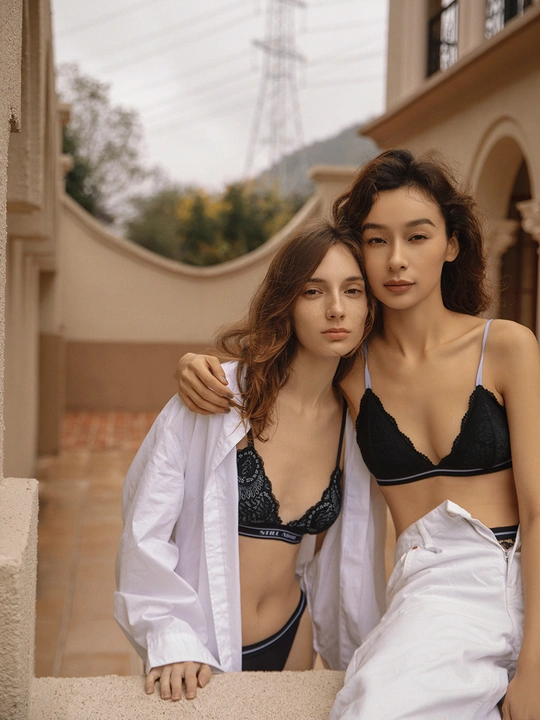 美丽的年轻女子穿着白色衬衫和比基尼站在一栋建筑物的阳台上