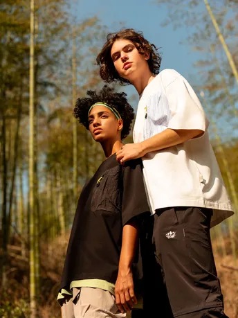 一个年轻男子站在森林里 旁边有一个年轻男孩。