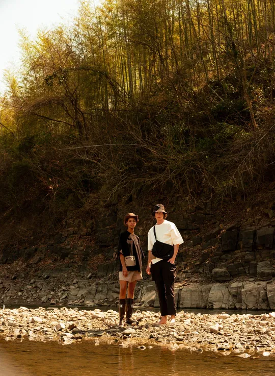 一位男子和一位女子站在岩石上 手拉手在一条小溪或河里。