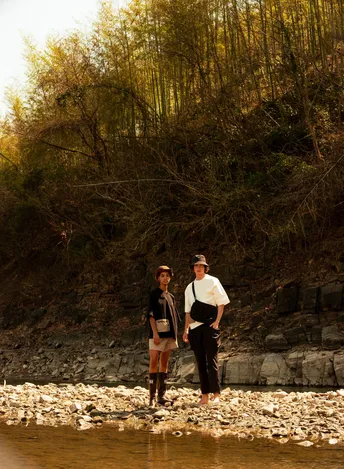 一位男子和一位女子站在岩石上 手拉手在一条小溪或河里。