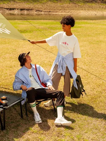 一名年轻男子拿着风筝站在一名女子旁边 女子坐在地上。