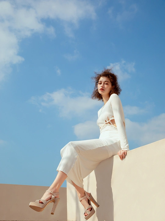 一个穿白色鞋子的女人坐在墙上