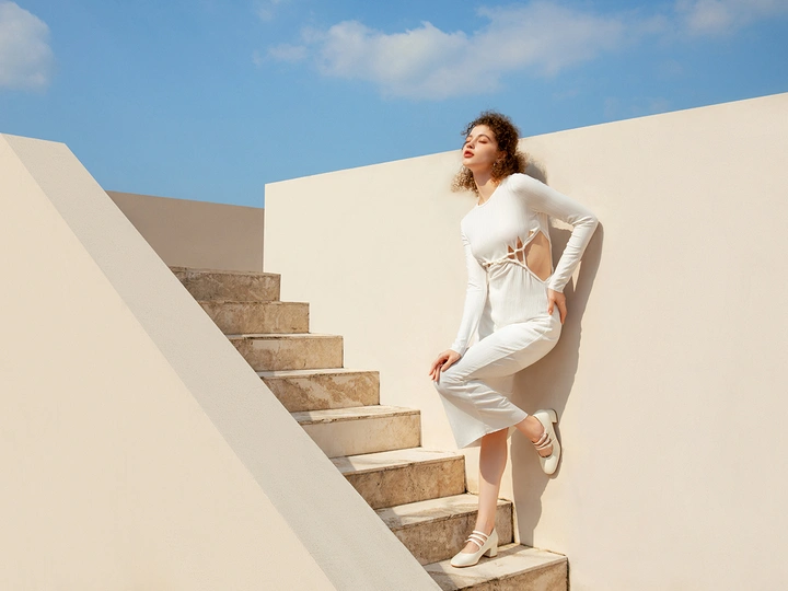 一个美丽的年轻女子穿着白色裙子爬楼梯