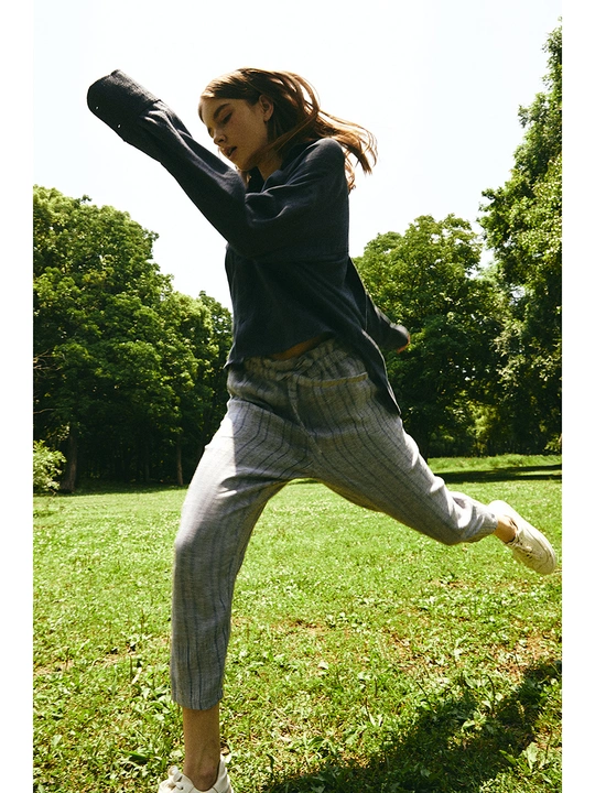 一个年轻女子在一个草地上扔飞盘 而另一个人站在她身后的草地上。