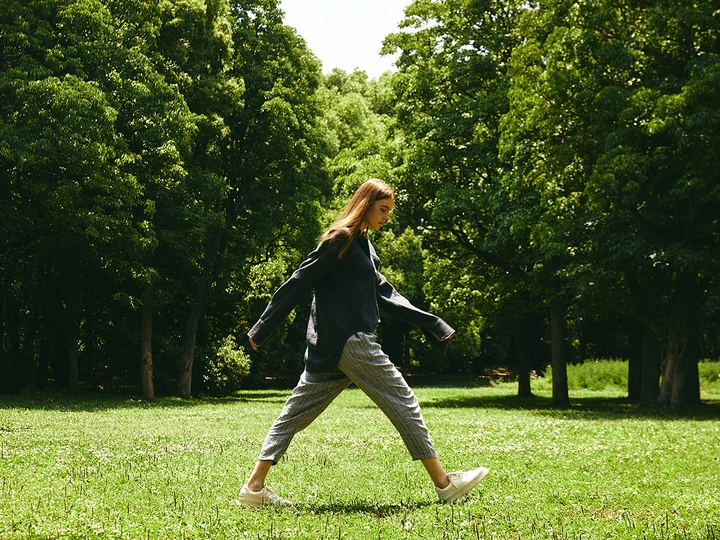 一位年轻女子在草地上与树木和绿草一起玩飞盘。