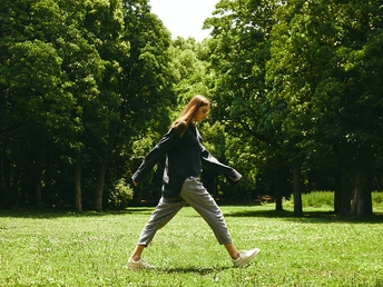 一位年轻女子在草地上与树木和绿草一起玩飞盘。