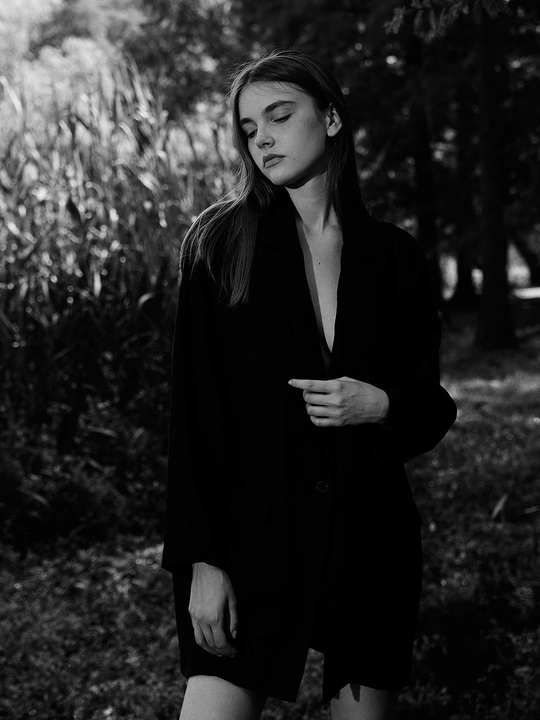 一个穿着黑色外套的年轻女子在森林中行走