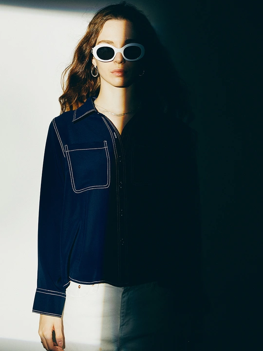 一位戴太阳镜和夹克的女人站立着