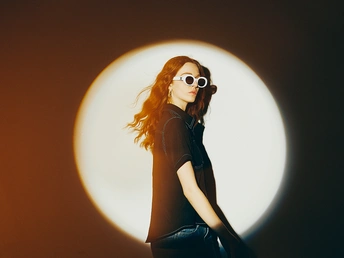 一位戴着太阳镜的年轻女子站在一盏灯前