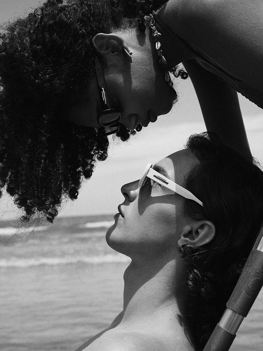 在海滩上 一个年轻女子在亲吻另一个年轻女子