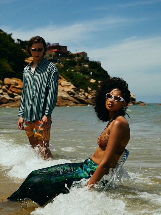 一个小男孩站在浅水处 一个妇女朝他走过来 在海滩上。