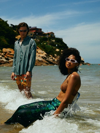 一个小男孩站在浅水处 一个妇女朝他走过来 在海滩上。