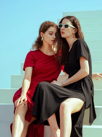 两个穿黑色连衣裙的年轻女子坐在长凳上