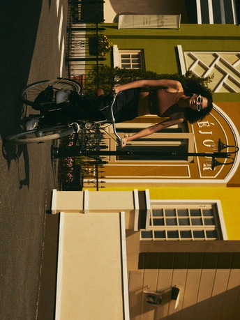 一个人骑着自行车 旁边有一座带钟楼的建筑物。