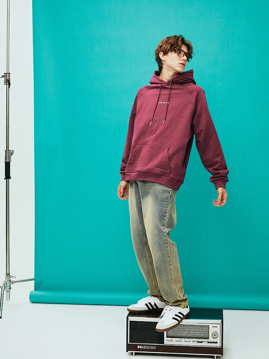 一个穿连帽衫的年轻人站在滑板车上