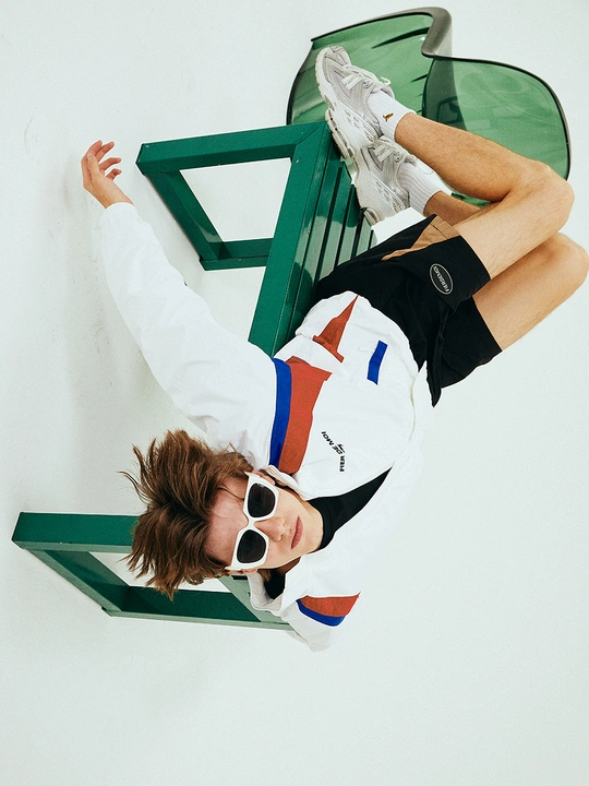 一个戴太阳镜的年轻人躺在绿色的长凳上