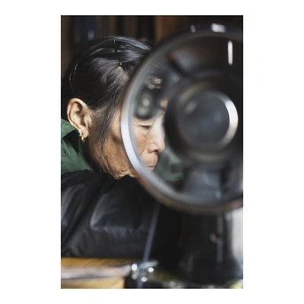 一位正在缝纫机前工作的女性低头看着