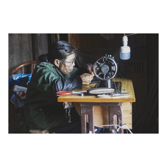 一个坐在桌子旁 正在缝纫机上工作的女人