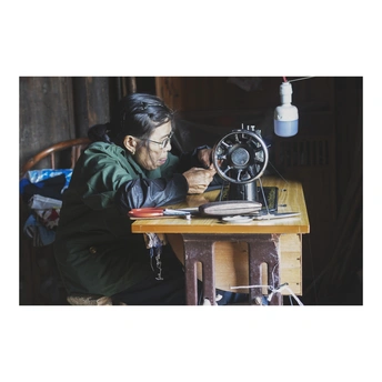 一个坐在桌子旁 正在缝纫机上工作的女人