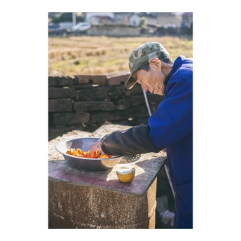 一个老人在一个碗里煮食物 一个年长的女人从它那里吃。