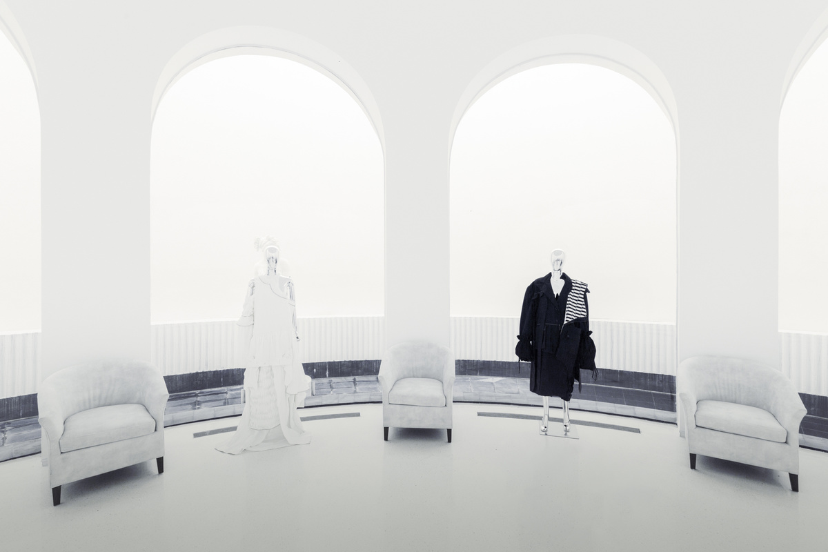 一个带有白色家具和大型窗户的房间 中间有一个模特站立。