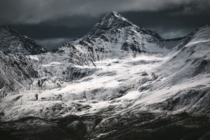 一个白雪皑皑的山脉 一个人站在山顶上。