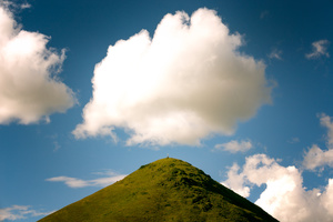 一片青翠的山丘 顶部覆盖着绿色的草地 在蔚蓝的天空中。