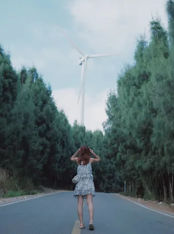 一位穿着连衣裙的年轻女子走向风车