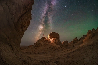 在沙漠中的洞穴中 一个人站在夜晚星空下 星星闪烁。