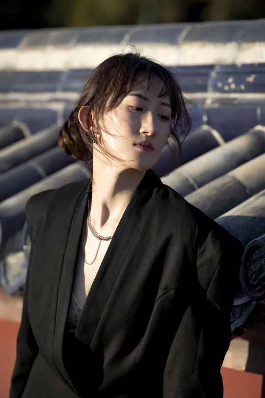 一位穿着黑色西装的年轻女子站在屋顶上