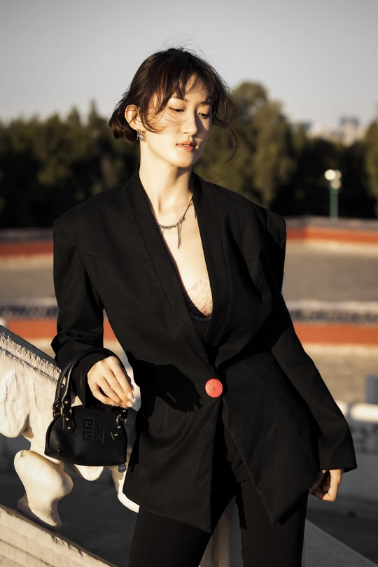 一位穿着黑色西装站在桥上的女人