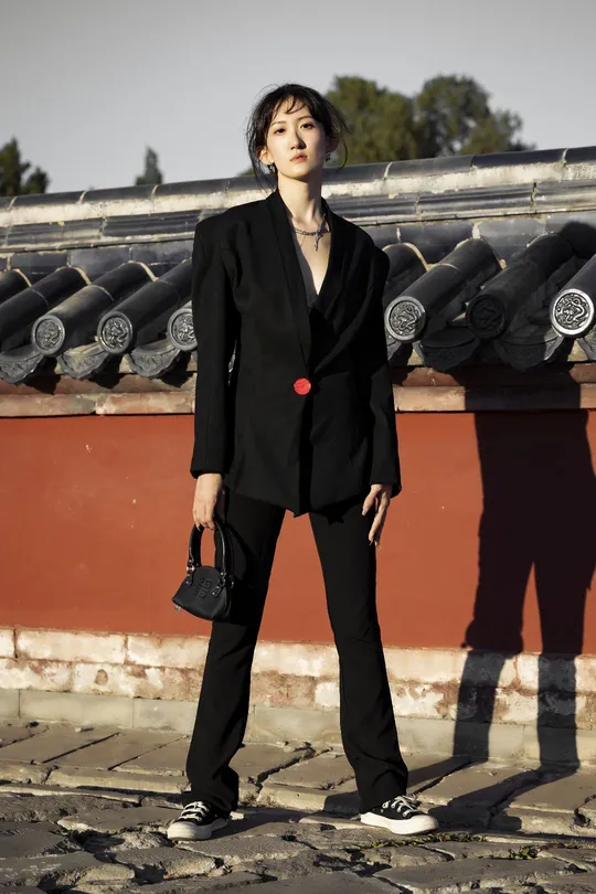 一位穿着黑色西装站在屋顶上的女人