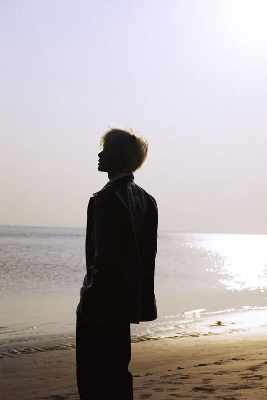 一个人和一个女人站在海滩上 朝向海洋