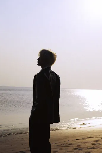 一个人和一个女人站在海滩上 朝向海洋