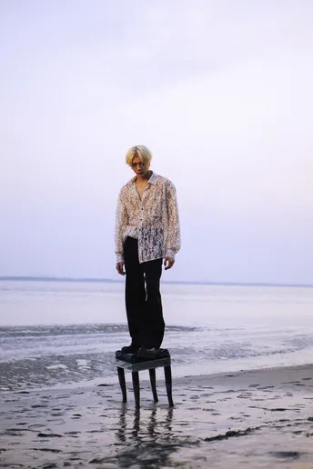 一位年长的妇女站在海滩上的一把椅子上