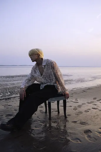 一个男子坐在海滩上的椅子上 一个女子坐在水中。