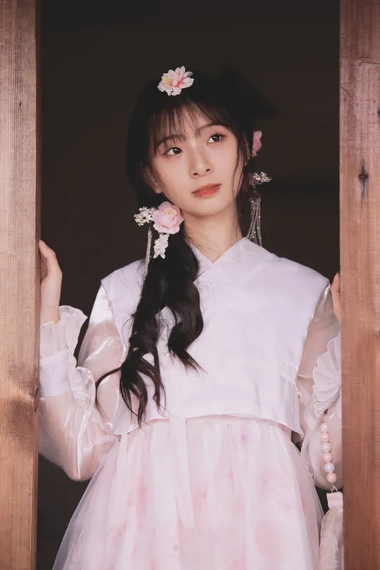 一位穿着传统白色连衣裙 头戴粉色花朵的年轻女子