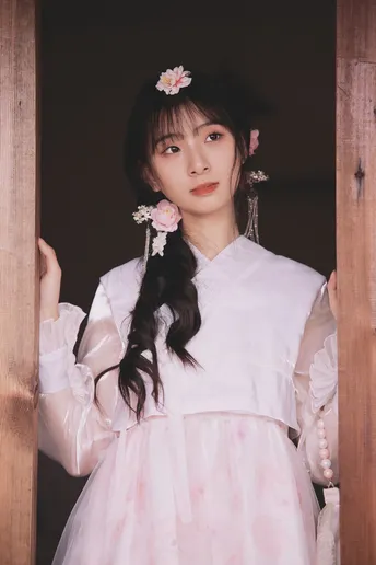 一位穿着传统白色连衣裙 头戴粉色花朵的年轻女子