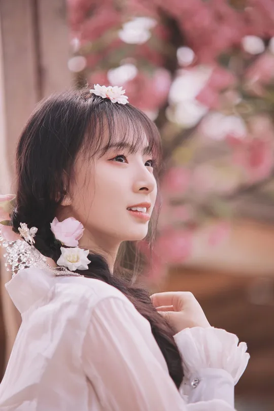 一位美丽的年轻女子穿着一件带有粉色花朵的白裙 