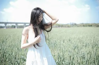 美丽的年轻女子穿着白色裙子站在麦田里