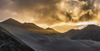 日落时一座白雪皑皑的山脉 阳光透过云层