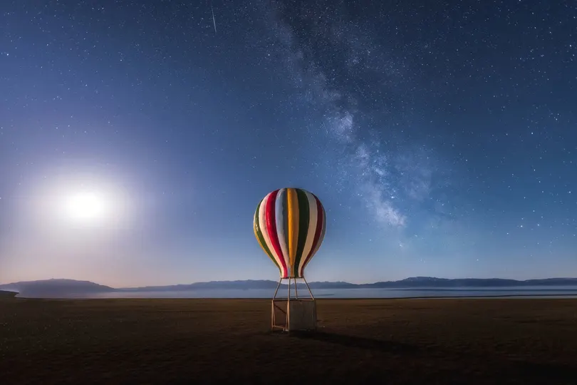 一个夜晚在湖上飘浮的热气球 天空中挂满满月和星星。